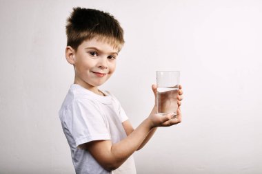 Gri arka plan üzerinde su bardağı ile küçük çocuk Stüdyo çekim