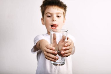 Gri arka plan üzerinde su bardağı ile küçük çocuk Stüdyo çekim