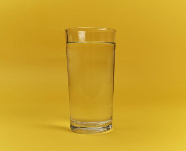 Sarı arka planda bir bardak su 