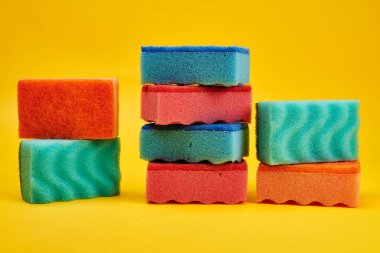 Sarı arka planda renkli yıkama süngerleri 