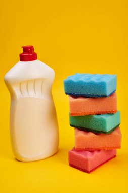 Sarı arka planda yıkama süngerleri ile temizleyici