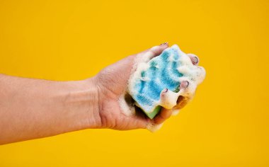 Sarı arka plan karşı köpüklü yıkama süngeri ile kadın Kırpma atış