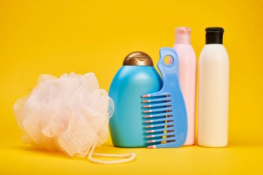 Sarı arka plan üzerinde saç şampuanı, sünger, saç fırçası ve jel duş Stüdyo çekim 