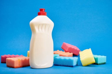 Mavi arka planda temizleyici ve sünger ile şişe