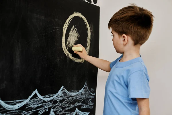 Μικρό Αγόρι Ζωγραφίζει Κιμωλία Μαύρο Σανίδα — Φωτογραφία Αρχείου