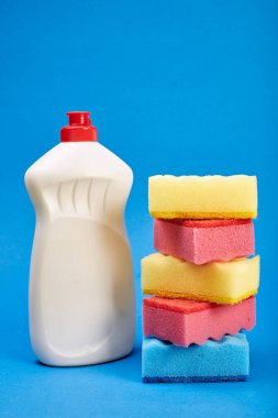 Mavi arka planda temizleyici ve sünger ile şişe