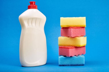 Mavi arka planda temizleyici ve sünger ile şişe