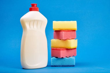 Mavi arka planda temizleyici ve sünger ile şişe