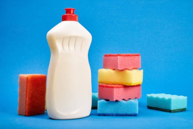 Mavi arka planda temizleyici ve sünger ile şişe