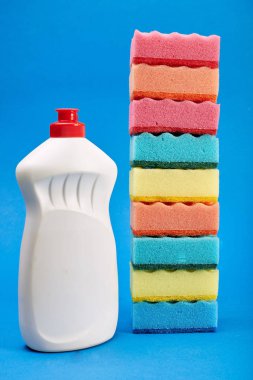 Mavi arka planda temizleyici ve sünger ile şişe