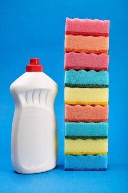 Mavi arka planda temizleyici ve sünger ile şişe