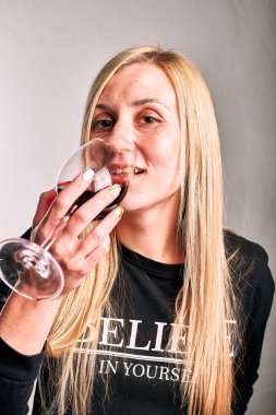 Gri arka planda şarap cam ile Muhteşem genç kadın 
