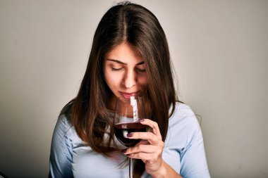 Gri arka planda şarap kadehi olan genç bir kadın. 