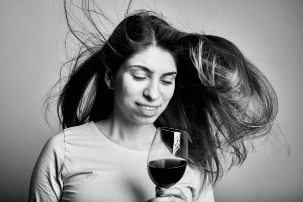 Black and white picture of woman with wine glass on grey background
