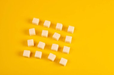 Sarı arka plan üzerinde düzenlenmiş şeker küpleri 