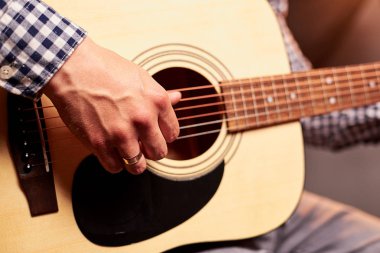 Akustik gitar çalan adamın kırpılmış çekimi 
