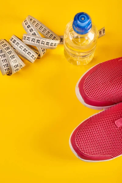 Sportive shoes with measuring tape and bottle of water, running concept