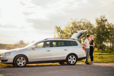 gezi sırasında birlikte araba bagajı yakınında duran güzel genç çift