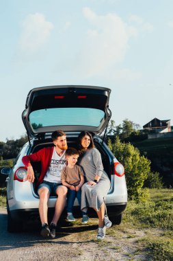 doğa üzerinde araba bagajında oturan güzel genç aile