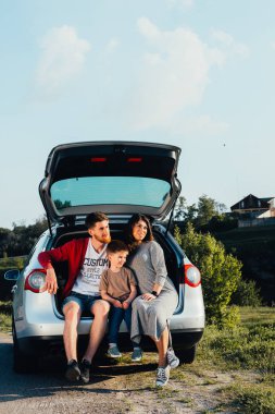 doğa üzerinde araba bagajında oturan güzel genç aile