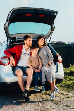 doğa üzerinde araba bagajında oturan güzel genç aile