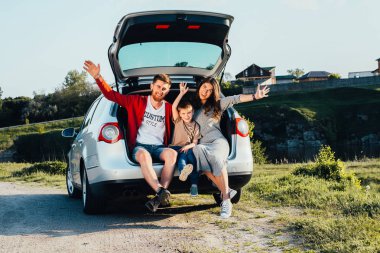 doğa üzerinde araba bagajında oturan güzel genç aile