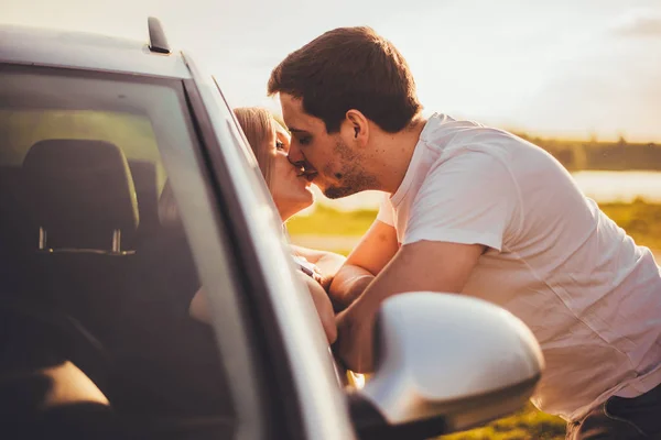 beautiful young couple kissing through car window during trip