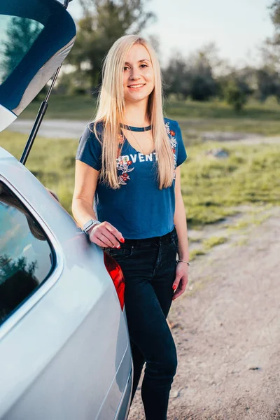 自然の上に車の近くに立っている美しい若い女性の肖像画 — ストック写真