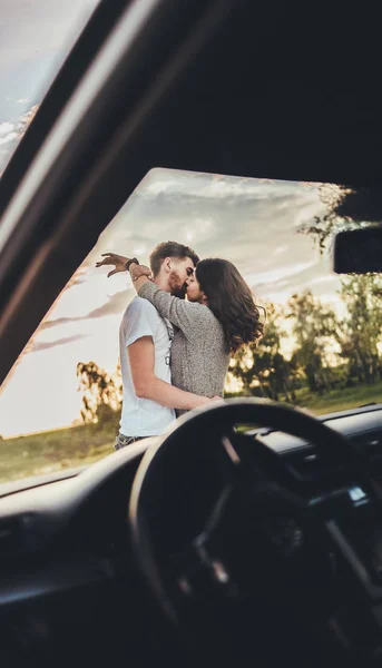beautiful young couple kissing near car during trip