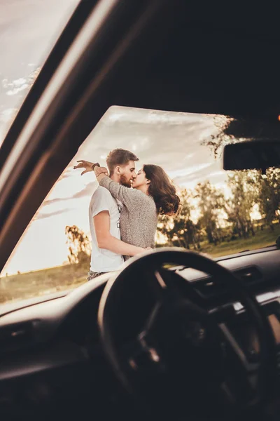 beautiful young couple kissing near car during trip