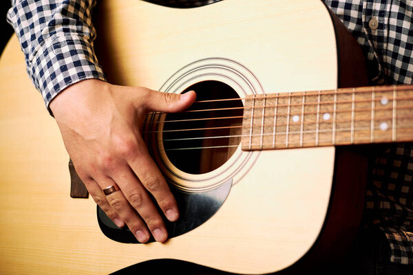 cropped shot of man playing acoustic guitar on black