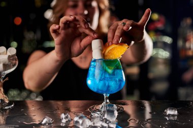 Barda mavi kokteyl yapan genç sarışın barmen kadın.