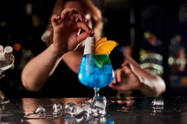 Barda mavi kokteyl yapan genç sarışın barmen kadın.