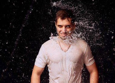 Karanlık arka planda genç adam su Sıçramaları