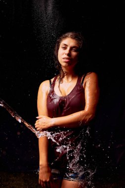 Karanlık arka planda genç kadın su Sıçramaları