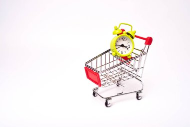 beyaz arka plan üzerinde çalar saat ile alışveriş arabası