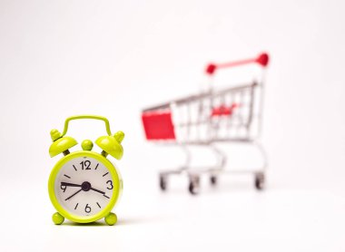 beyaz arka plan üzerinde çalar saat ile alışveriş arabası
