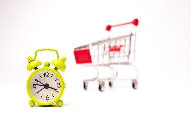 beyaz arka plan üzerinde çalar saat ile alışveriş arabası