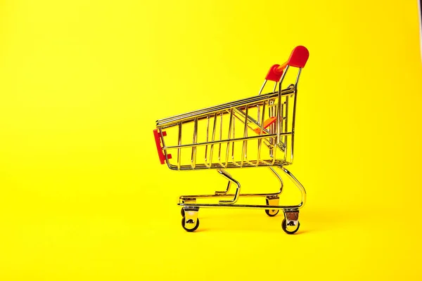 黄色の背景にショッピング トロリー — ストック写真