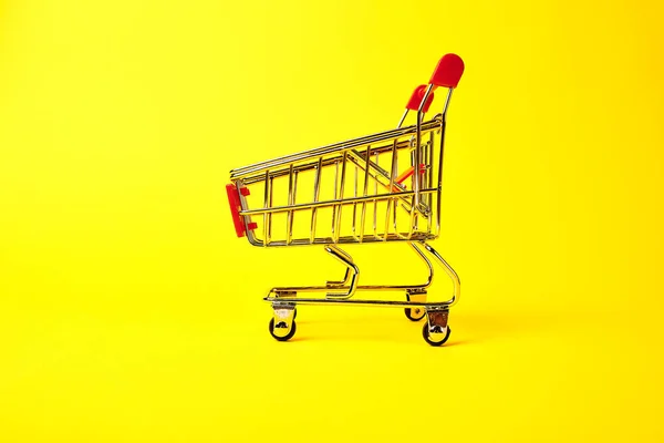 黄色の背景にショッピング トロリー — ストック写真