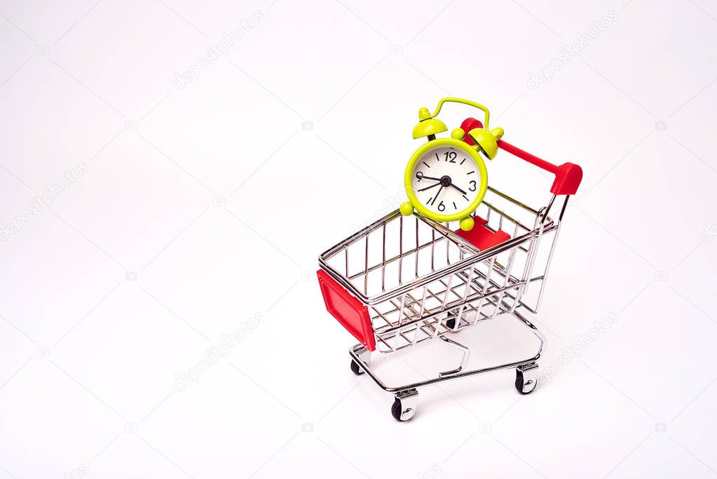 shopping trolley with alarm clock on white background