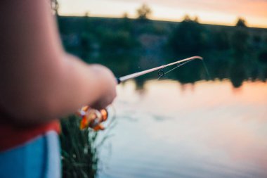 Genç adam nehirde balık tutuyor.