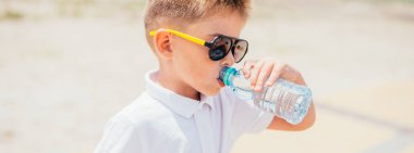 Sevimli küçük çocuk plajda su içme