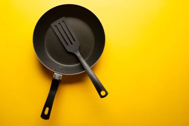 Boş tava, sarı bir arka plan üzerinde yemekler için spatula