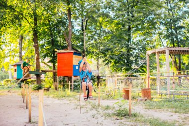 Küçük sevimli çocuk bir yaz güneşli bir günde bir tırmanma macera parkı aktivite zevk. Kask ve sigorta ile ekstrem spor tırmanma