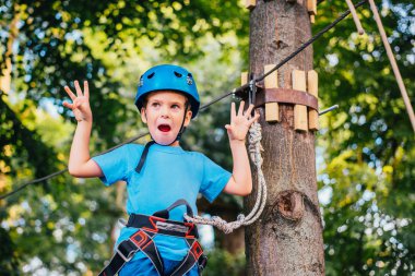 Küçük sevimli çocuk bir yaz güneşli bir günde bir tırmanma macera parkı aktivite zevk. Kask ve sigorta ile ekstrem spor tırmanma