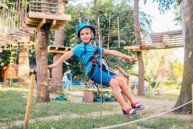 Küçük sevimli çocuk bir yaz güneşli bir günde bir tırmanma macera parkı aktivite zevk. Kask ve sigorta ile ekstrem spor tırmanma