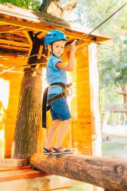 Küçük sevimli çocuk bir yaz güneşli bir günde bir tırmanma macera parkı aktivite zevk. Kask ve sigorta ile ekstrem spor tırmanma