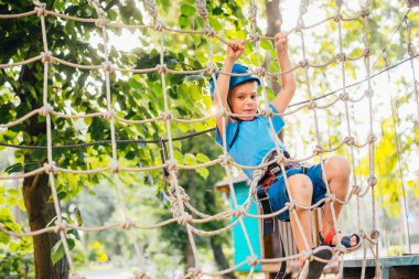 Küçük sevimli çocuk bir yaz güneşli bir günde bir tırmanma macera parkı aktivite zevk. Kask ve sigorta ile ekstrem spor tırmanma