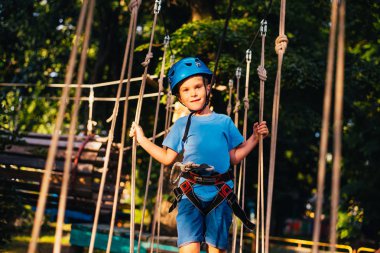 Küçük sevimli çocuk bir yaz güneşli bir günde bir tırmanma macera parkı aktivite zevk. Kask ve sigorta ile ekstrem spor tırmanma